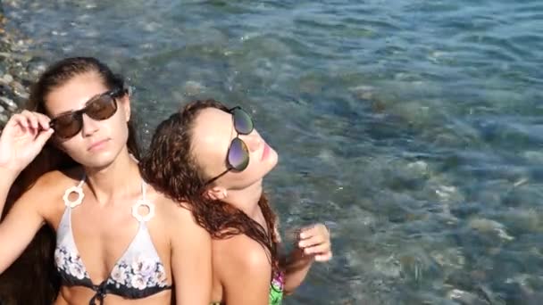 Dos amigas sexys, morena y pelirroja se están divirtiendo en el mar. Espolvorear el uno al otro con agua y divertirse. En cámara lenta. 4K . — Vídeo de stock