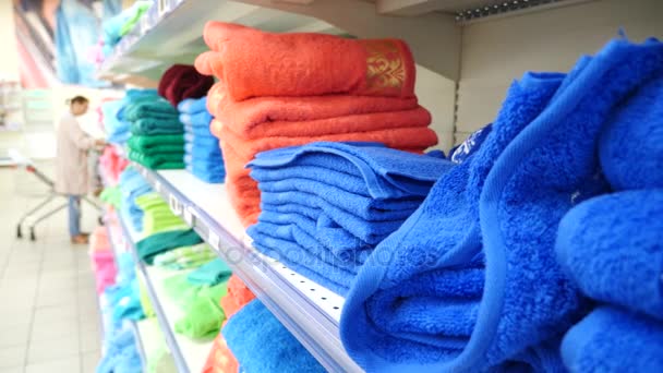 Молода дівчина вибирає банні рушники текстильні в супермаркеті магазину одягу, 4k. Повільний рух — стокове відео
