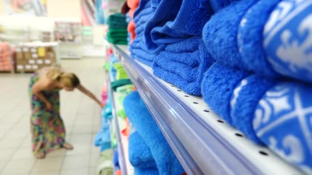Νεαρό κορίτσι επιλέγοντας μπάνιο πετσέτες υφασμάτων στα ενδύματα ρούχα κατάστημα σούπερ μάρκετ, 4k. Αργή κίνηση — Αρχείο Βίντεο
