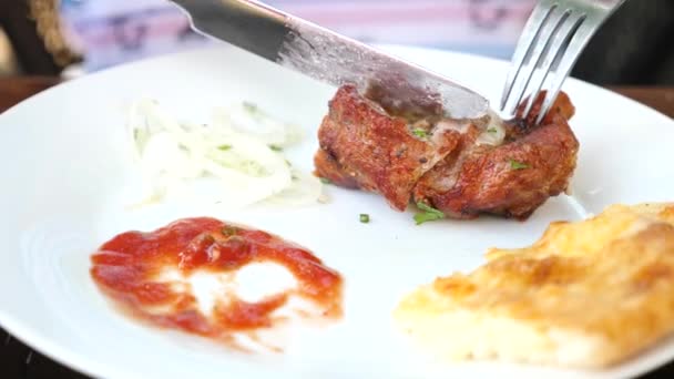 L'uomo con un coltello taglia la bistecca su un piatto in un ristorante, primo piano, 4k, rallentatore — Video Stock