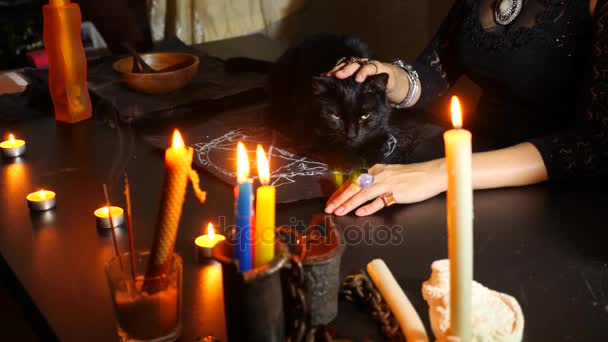 Ведьма гадалка со свечами крупным планом. Волшебный ритуал с черной кошкой. Предсказание. Хэллоуин, 4к, замедленная съемка — стоковое видео