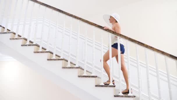 Žena v velký bílý klobouk vejde se velké bílé schodiště. 4 k. Zpomalený pohyb