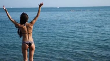 Bikinili seksi kız denizde kameraya onu geri ile ayakta su sıçramalarına, onun ince rakam ve elastik kalça görülebilir. Ağır çekim, 4k.