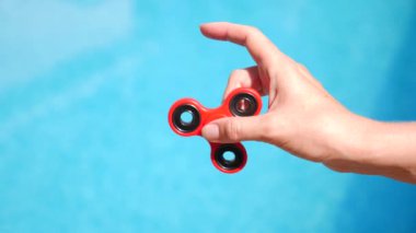 Kırmızı el spinner veya kişi kol üzerinde dönen getiriyor. Kıpır Spinner mavi su havuzunda bir arka plan üzerinde dönen bir kadın. 4 k. ağır çekim