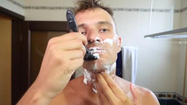 Adam yüzünü tıraş. yakışıklı adam banyoda tıraş. 4k, ağır çekim