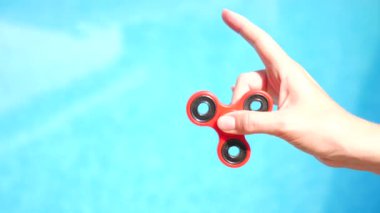 Kırmızı el spinner veya kişi kol üzerinde dönen getiriyor. Kıpır Spinner mavi su havuzunda bir arka plan üzerinde dönen bir kadın. 4 k. ağır çekim