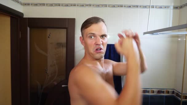 Мужчина поет и танцует возле зеркала в ванной комнате во время утреннего туалета. 4k, slow motion — стоковое видео