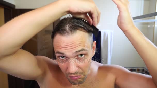 Giovane uomo attraente ispeziona un reclinazione dei capelli in bagno. Calvizie. 4k, rallentatore — Video Stock