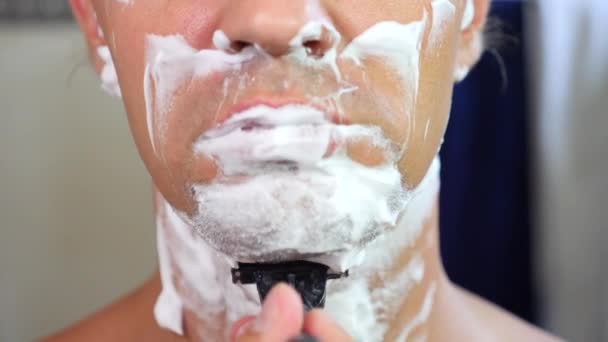 Ο άνθρωπος ξυρίζει το πρόσωπό του. όμορφος άνδρας ξυρίσματος στο λουτρό. 4k, αργή κίνηση — Αρχείο Βίντεο