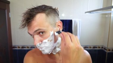 Adam yüzünü tıraş. yakışıklı adam banyoda tıraş. 4k, ağır çekim