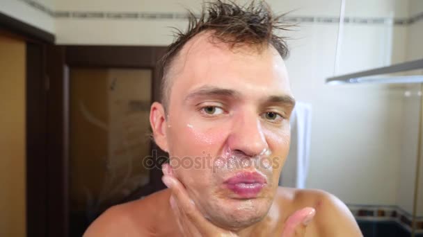 Hombre se afeita la cara. hombre guapo afeitándose en el baño. 4k, cámara lenta — Vídeos de Stock