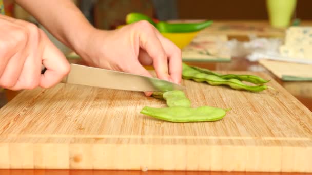 Vrouwelijke handen met een mes gesneden een string bean op een houten bord. 4 k. Slowmotion — Stockvideo