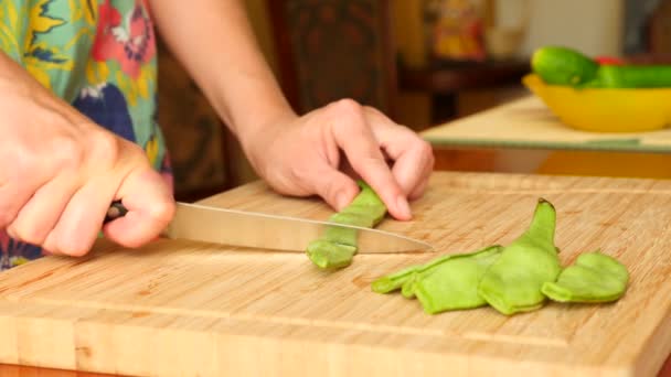 Les mains féminines avec le couteau coupent le haricot sur la planche en bois. 4k. Mouvement lent — Video