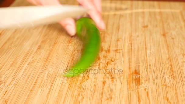 Vrouwelijke handen met een mes uitgesneden hete peper op een houten bord. 4 k. Slowmotion — Stockvideo