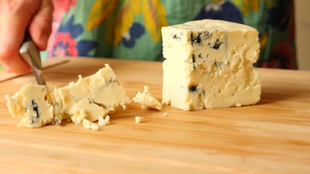 Les mains féminines avec un couteau découpent le fromage avec un moule bleu sur une planche en bois. 4k. Mouvement lent — Video