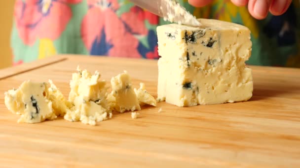 Les mains féminines avec un couteau découpent le fromage avec un moule bleu sur une planche en bois. 4k. Mouvement lent — Video