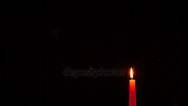 Closeup of candle on black. Someone blows out the flame of a red candle. 4K. Slow motion — Stock Video