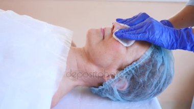 Yaşlı kadın yüz maskesi alma için Spa terapi. 4 k. ağır çekim. Bir güzellik uzmanı alımı