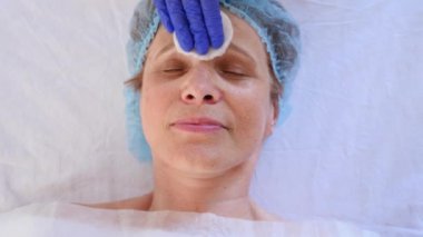 Yaşlı kadın yüz maskesi alma için Spa terapi. 4 k. ağır çekim. Bir güzellik uzmanı alımı