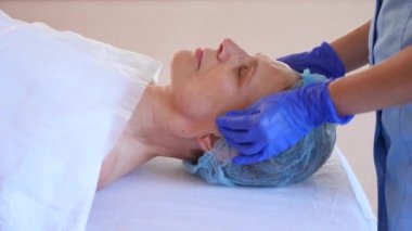 Yaşlı kadın yüz maskesi alma için Spa terapi. 4 k. ağır çekim. Bir güzellik uzmanı alımı