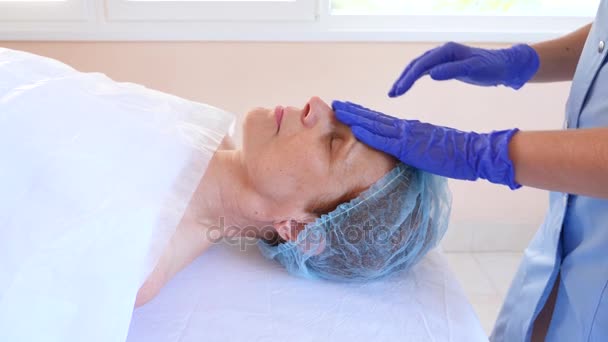 Terapia de spa para mujeres mayores que reciben mascarilla facial. 4k. En cámara lenta. Recepción de un cosmetólogo — Vídeo de stock