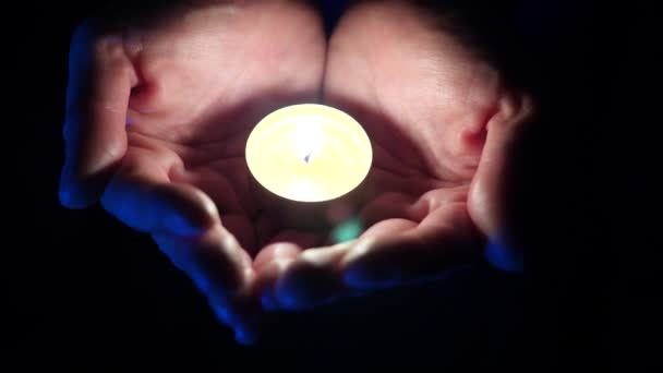 Closeup of an aromatic little candle in the palms of a man on black. 4 k. Slow-motion shooting. — Stock Video