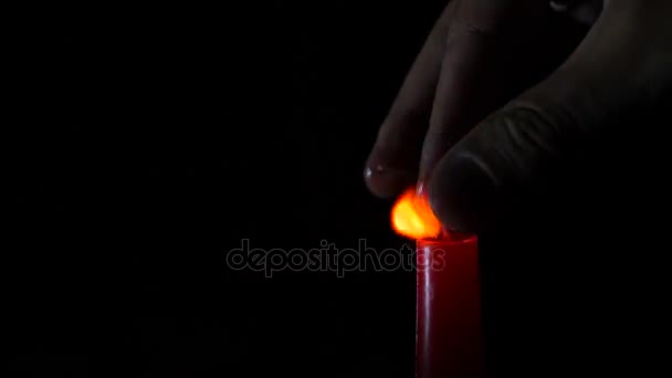 Closeup of candle on black. Someone extinguishes the flame of a red candle with his fingers. 4 k. Slow-motion shooting — Stock Video