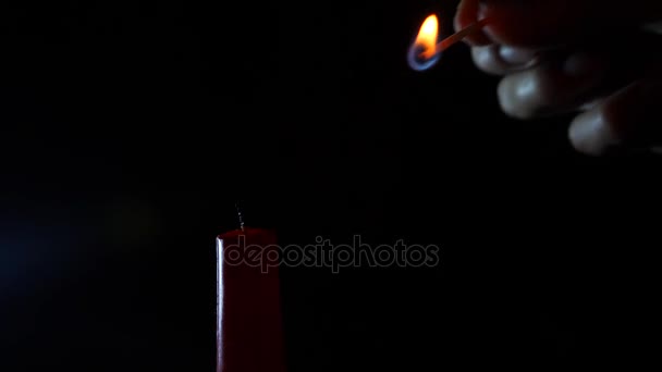 Closeup of candle on black. Someone lights a candle with a flame from a match. 4 k. Slow-motion shooting — Stock Video