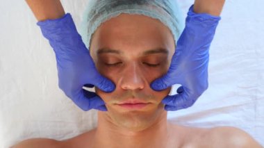 Yakışıklı erkekler yüz maskesi alma için spa terapisi. 4 k. ağır çekim. Bir güzellik uzmanı alımı