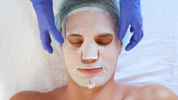 Terapia de spa para hombres guapos que reciben máscara facial. 4k. En cámara lenta. Recepción de un cosmetólogo — Vídeo de stock