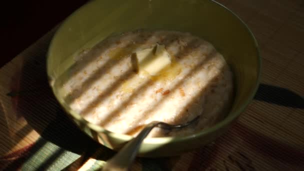 オートミールとバターを溶かしてプレート。ブラインドから影の背景。家での朝食。4 k. スローモーション撮影 — ストック動画