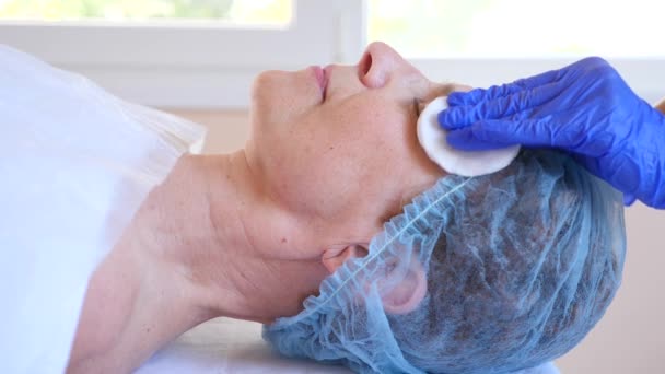 Terapia de spa para mujeres mayores que reciben mascarilla facial. 4k. En cámara lenta. Recepción de un cosmetólogo — Vídeos de Stock