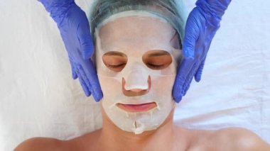 Yakışıklı erkekler yüz maskesi alma için spa terapisi. 4 k. ağır çekim. Bir güzellik uzmanı alımı