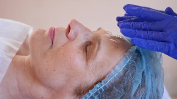 Terapia termale per donna anziana che riceve maschera facciale. 4k. Al rallentatore. Ricezione di un cosmetologo — Video Stock