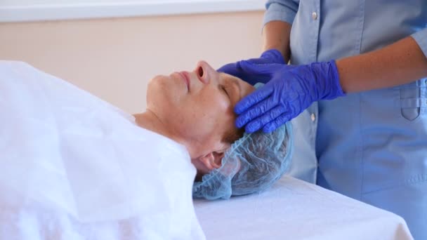 Terapia de spa para mujeres mayores que reciben mascarilla facial. 4k. En cámara lenta. Recepción de un cosmetólogo — Vídeos de Stock