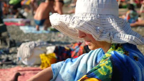 Mujer mayor activa y feliz con sombrero de ala ancha. Mirando al mar. 4k. Movimiento lento — Vídeo de stock