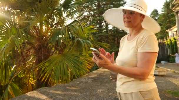 Güzel yaşlı kadın ya da turistik bir fotoğraf ile mobil cep telefonu akıllı telefon alıyor. Kadın sosyal medya fotoğraf sitesi pic paylaşmak için. 4 k. ağır çekim — Stok video