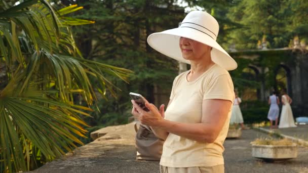 Hermosa anciana o turista tomando una fotografía con teléfono móvil. Señora para compartir foto en las redes sociales sitio de fotos. 4k. Movimiento lento — Vídeos de Stock