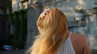 Güzel kadın styling saç açık havada. Ağır çekim. Parkta eğleniyor, doğanın keyfini, Rüzgar ile oynarken uzun sağlıklı saçları mutlu sakin çekici kız. Yakın çekim. 4k