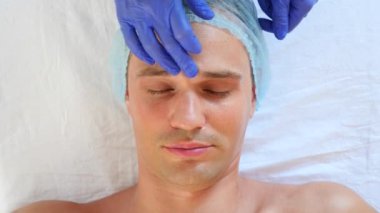 Yakışıklı erkekler yüz maskesi alma için spa terapisi. 4 k. ağır çekim. Bir güzellik uzmanı alımı