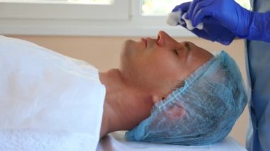 Yakışıklı erkekler yüz maskesi alma için spa terapisi. 4 k. ağır çekim. Bir güzellik uzmanı alımı