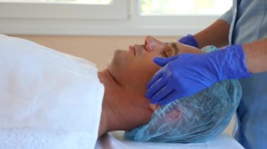 Yakışıklı erkekler yüz maskesi alma için spa terapisi. 4 k. ağır çekim. Bir güzellik uzmanı alımı
