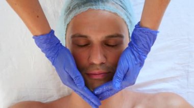 Yakışıklı erkekler yüz maskesi alma için spa terapisi. 4 k. ağır çekim. Bir güzellik uzmanı alımı