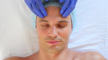 Yakışıklı erkekler yüz maskesi alma için spa terapisi. 4 k. ağır çekim. Bir güzellik uzmanı alımı