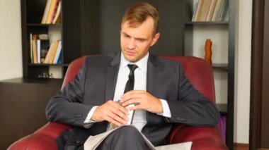 İşadamı bir sandalyede oturuyor ve bir gazete okuyor. Alkol bir şişe içki. O mutsuz ve etkileyici. 4'e. Ağır çekim.