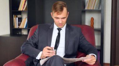 İşadamı bir sandalyede oturuyor ve bir gazete okuyor. Alkol bir şişe içki. O mutsuz ve etkileyici. 4'e. Ağır çekim.