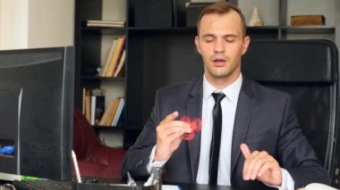 Kırmızı el spinner veya üzerinde dönen fidgeting spinner el mans. Onun masasında ofisinde topluca spinner iplik elbiseli adam. Burun üzerinde katlanmış. 4 k. ağır çekim