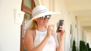 Güzel kadın dansları sokakta vitrin, yanındaki telefon kulaklık müzik dinlemek, holding nerede indirimler ve satış. Ağır çekim. 4k