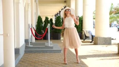 Güzel kadın dansları sokakta vitrin, yanındaki telefon kulaklık müzik dinlemek, holding nerede indirimler ve satış. Ağır çekim. 4k