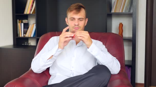 Rode hand spinner of fidgeting spinner, roterende op mans hand. Man in een pak spinnen een fidget spinner in zijn kantoor achter zijn bureau. Wendingen op de neus. 4 k. Slowmotion — Stockvideo